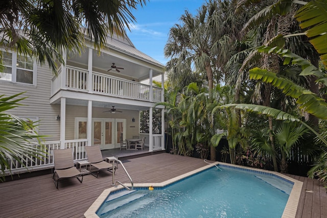 view of swimming pool featuring a deck, ceiling fan, and french doors