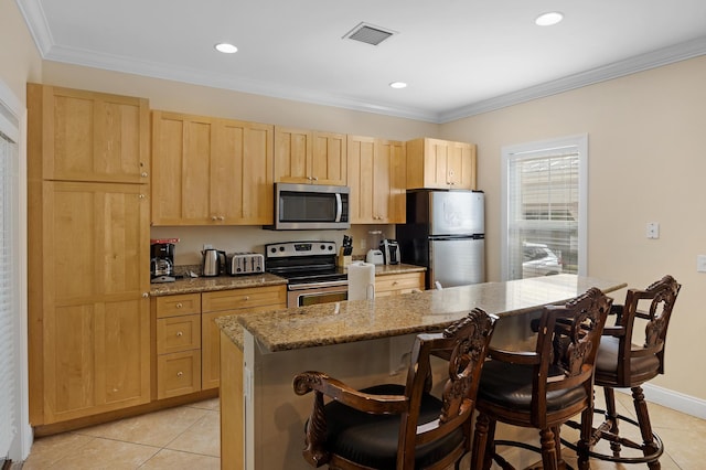 kitchen featuring a kitchen breakfast bar, a center island, stainless steel appliances, crown molding, and light stone countertops