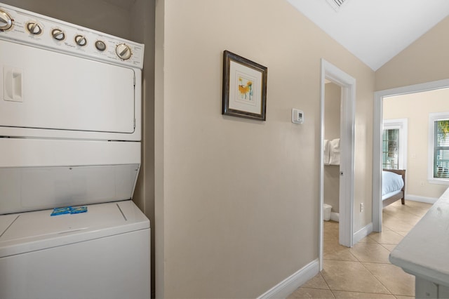 clothes washing area featuring light tile patterned flooring and stacked washer and clothes dryer