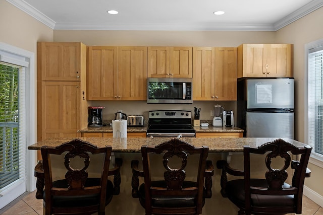 kitchen with a kitchen breakfast bar, appliances with stainless steel finishes, light brown cabinetry, and light stone counters