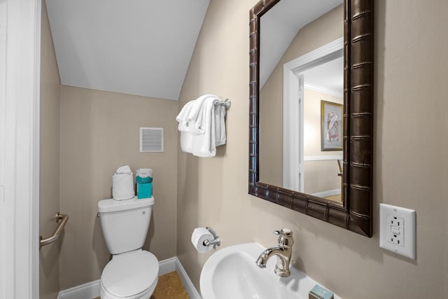 bathroom featuring sink, vaulted ceiling, and toilet