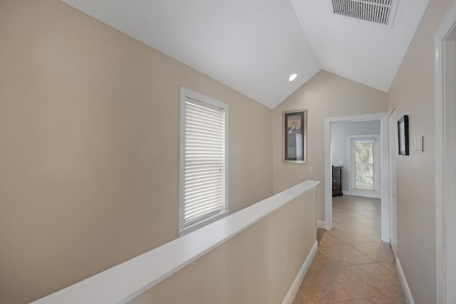 hallway featuring vaulted ceiling and light tile patterned flooring