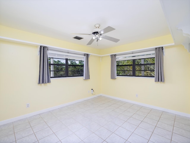 unfurnished room featuring a wealth of natural light, visible vents, baseboards, and a ceiling fan