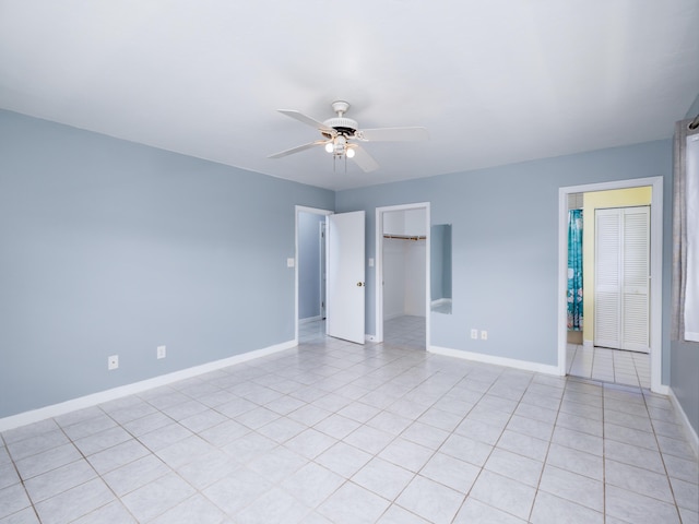 empty room featuring light tile patterned flooring, a ceiling fan, and baseboards