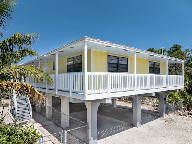 view of side of property with a carport, covered porch, stairs, and a gate