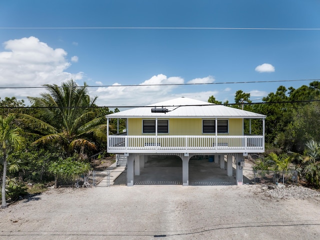 beach home featuring stairway, a carport, driveway, and fence