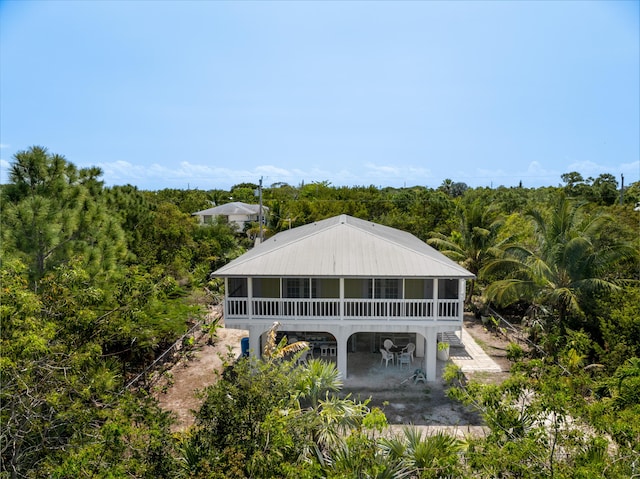 rear view of house with a patio, a wooded view, and a sunroom