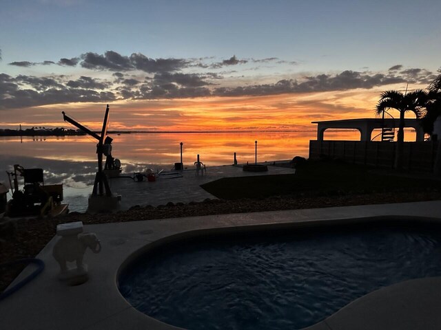 pool at dusk featuring a water view