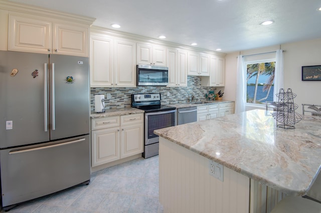 kitchen with light stone counters, sink, tasteful backsplash, and appliances with stainless steel finishes