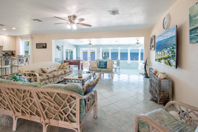 living room featuring light tile patterned floors, a textured ceiling, and french doors