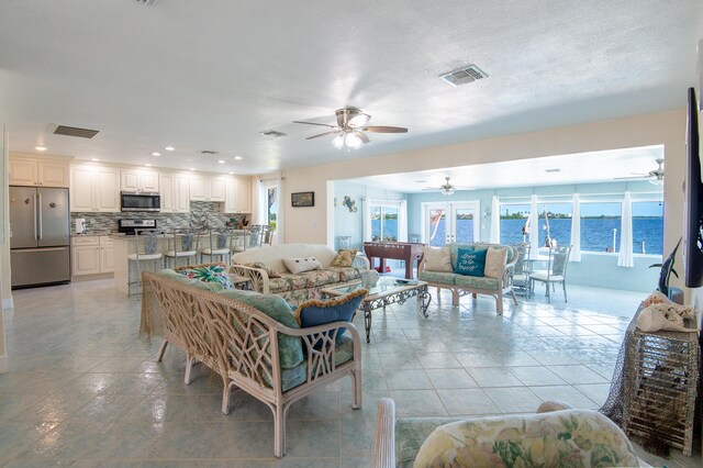 living room with a water view, ceiling fan, and light tile patterned floors