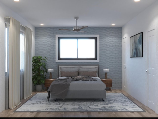 bedroom featuring ceiling fan, multiple windows, and light wood-type flooring