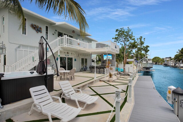 dock area with a hot tub and a patio area