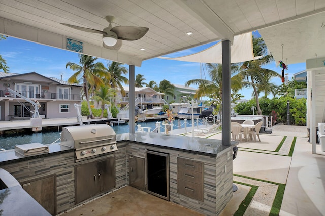 view of patio / terrace featuring a grill, an outdoor bar, a water view, and exterior kitchen