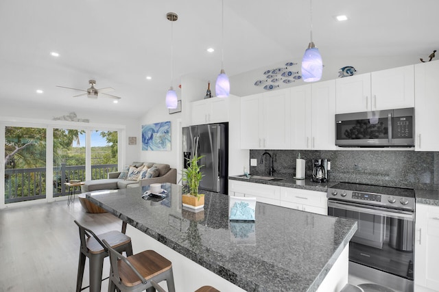 kitchen featuring appliances with stainless steel finishes, sink, white cabinets, and a kitchen breakfast bar