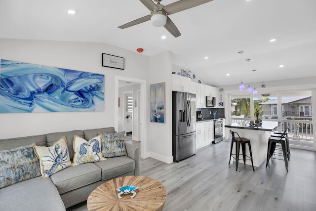 living room featuring ceiling fan, lofted ceiling, and light wood-type flooring