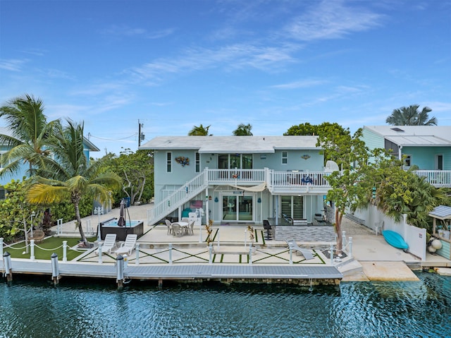 rear view of property with a deck with water view and a patio