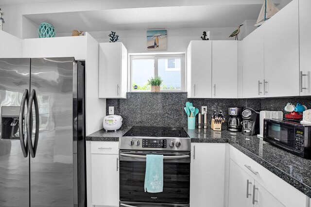 kitchen featuring tasteful backsplash, dark stone counters, white cabinets, and appliances with stainless steel finishes