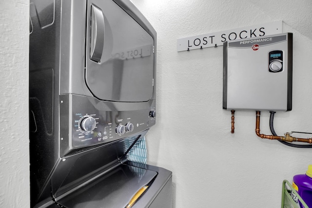 washroom with water heater and stacked washer and clothes dryer