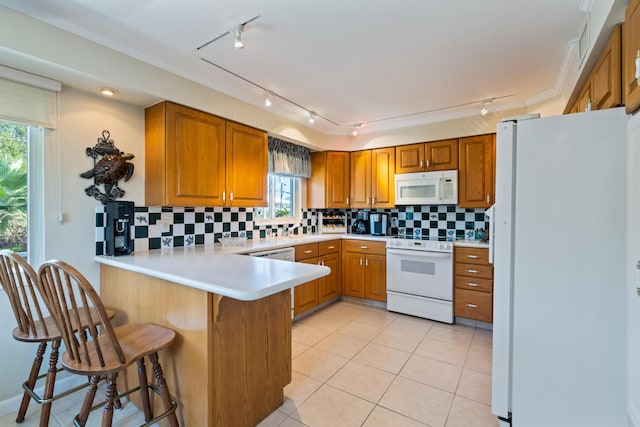 kitchen featuring a breakfast bar, decorative backsplash, light tile patterned floors, kitchen peninsula, and white appliances