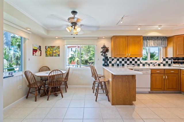 kitchen featuring light tile patterned floors, white dishwasher, tasteful backsplash, ornamental molding, and kitchen peninsula