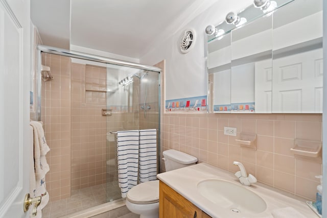 bathroom with vanity, toilet, a shower with shower door, and tile walls