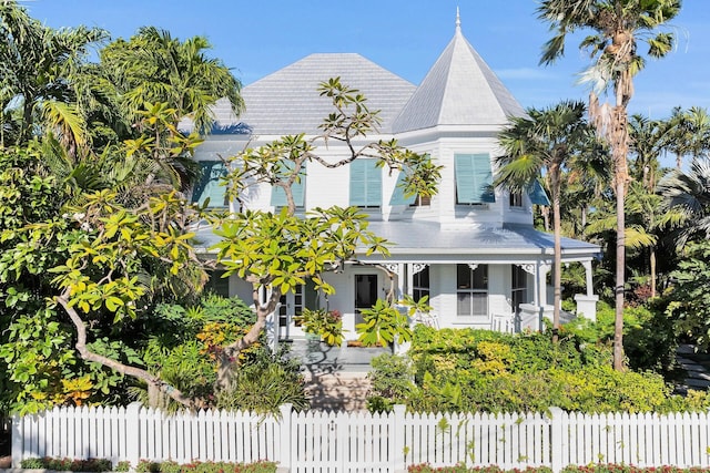 victorian house featuring covered porch and a fenced front yard
