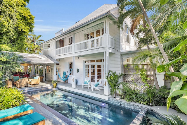 rear view of property featuring a jacuzzi, french doors, and a balcony