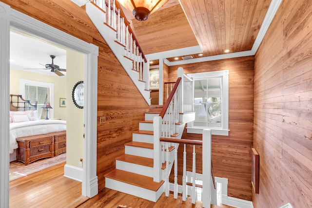 stairs with wood ceiling, ceiling fan, wood-type flooring, and wood walls