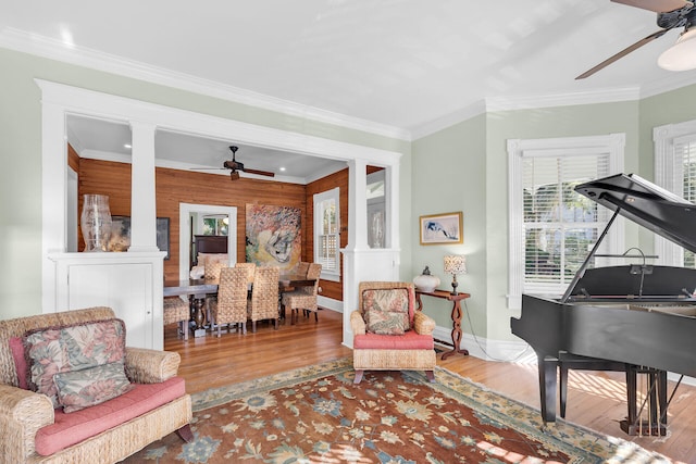 living area with crown molding, ceiling fan, decorative columns, and hardwood / wood-style floors