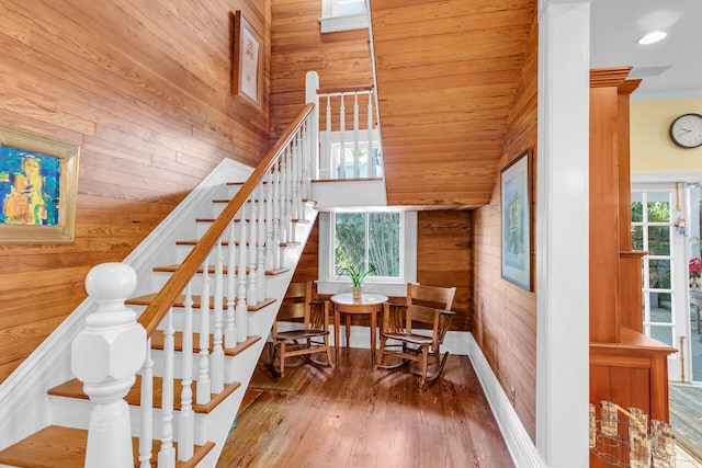 stairs featuring hardwood / wood-style flooring, crown molding, and wood walls