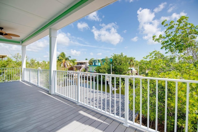 deck with a water view and ceiling fan