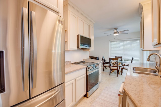 kitchen featuring ceiling fan, light stone countertops, stainless steel appliances, light speckled floor, and a sink