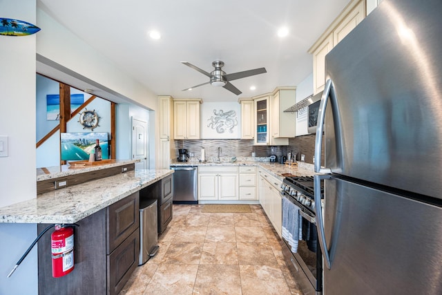 kitchen featuring appliances with stainless steel finishes, tasteful backsplash, ceiling fan, light stone counters, and cream cabinetry