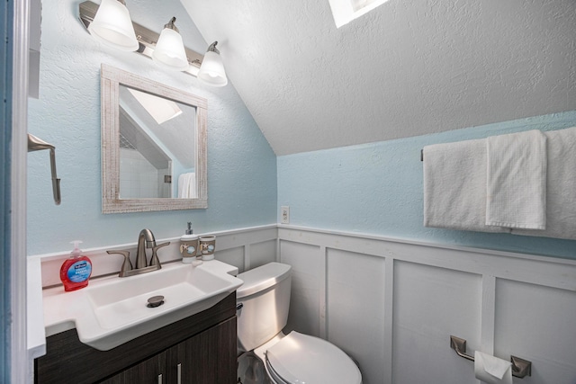 bathroom with lofted ceiling, vanity, toilet, and a textured ceiling