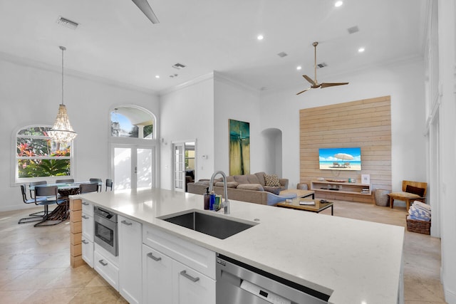 kitchen featuring sink, appliances with stainless steel finishes, hanging light fixtures, ornamental molding, and white cabinets