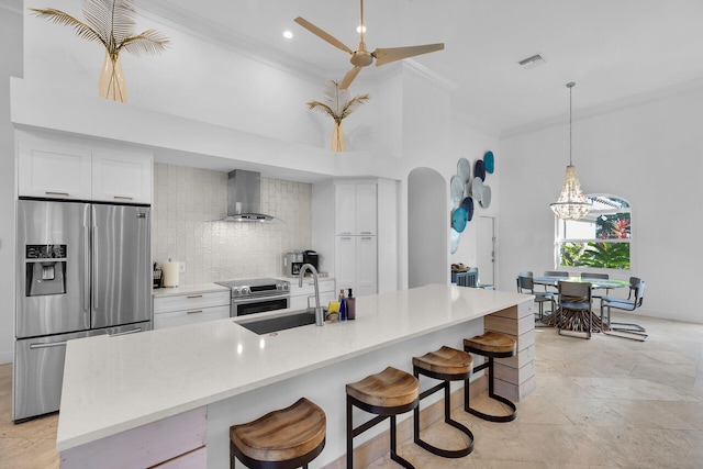 kitchen with wall chimney exhaust hood, white cabinetry, and stainless steel appliances