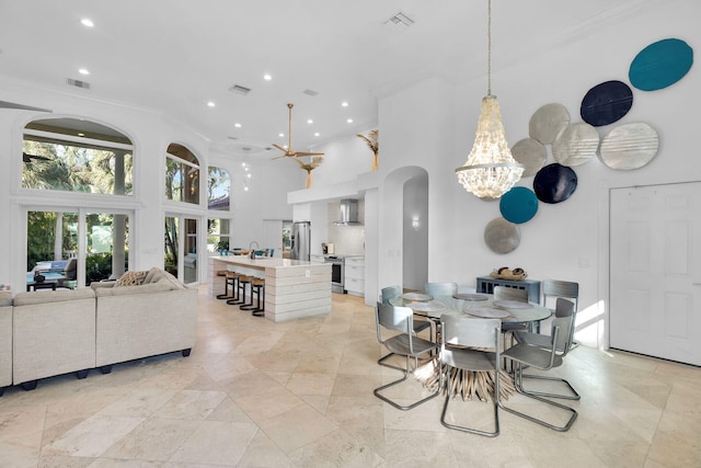 dining space featuring a notable chandelier, ornamental molding, and a high ceiling