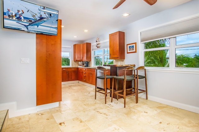 kitchen featuring dishwasher, ceiling fan, a kitchen bar, and kitchen peninsula