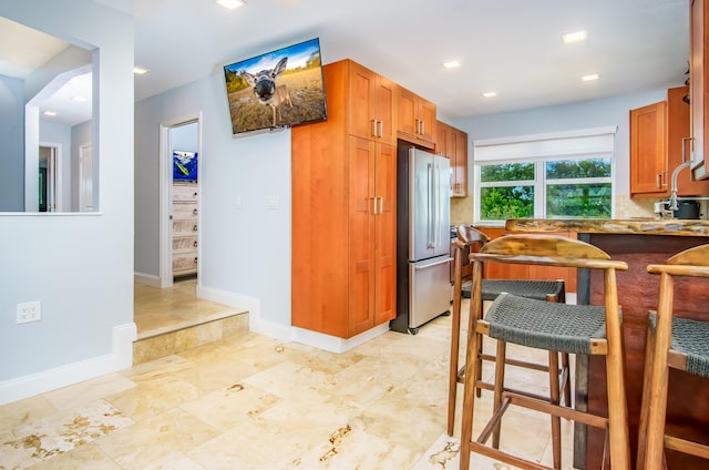 kitchen featuring tasteful backsplash, high quality fridge, a breakfast bar, and sink