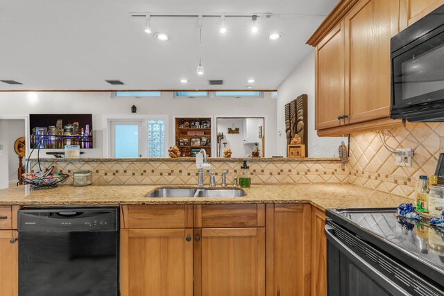 kitchen featuring light stone counters, sink, backsplash, and black appliances