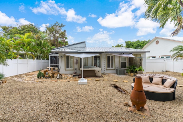 rear view of property featuring central AC and a hot tub