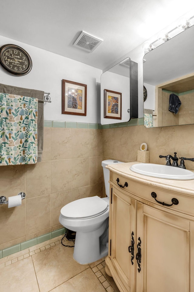 bathroom with vanity, toilet, tile patterned flooring, and tile walls