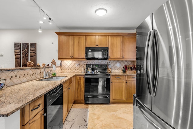 kitchen with sink, black appliances, kitchen peninsula, light stone countertops, and backsplash