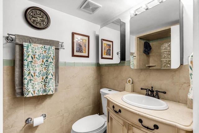 bathroom with vanity, tile walls, and toilet