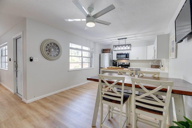 kitchen featuring appliances with stainless steel finishes, pendant lighting, white cabinetry, butcher block counters, and light hardwood / wood-style flooring