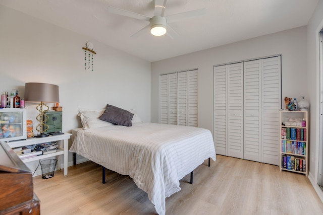 bedroom featuring ceiling fan, multiple closets, and light wood-type flooring