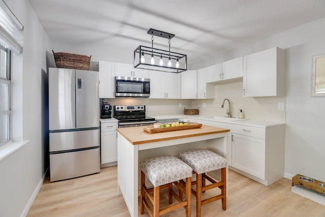 kitchen featuring sink, a breakfast bar area, stainless steel appliances, white cabinets, and a kitchen island