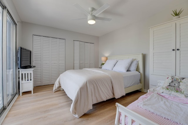 bedroom with ceiling fan, light hardwood / wood-style flooring, and multiple closets