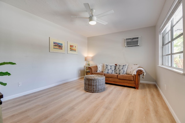 sitting room with ceiling fan, an AC wall unit, and light hardwood / wood-style floors